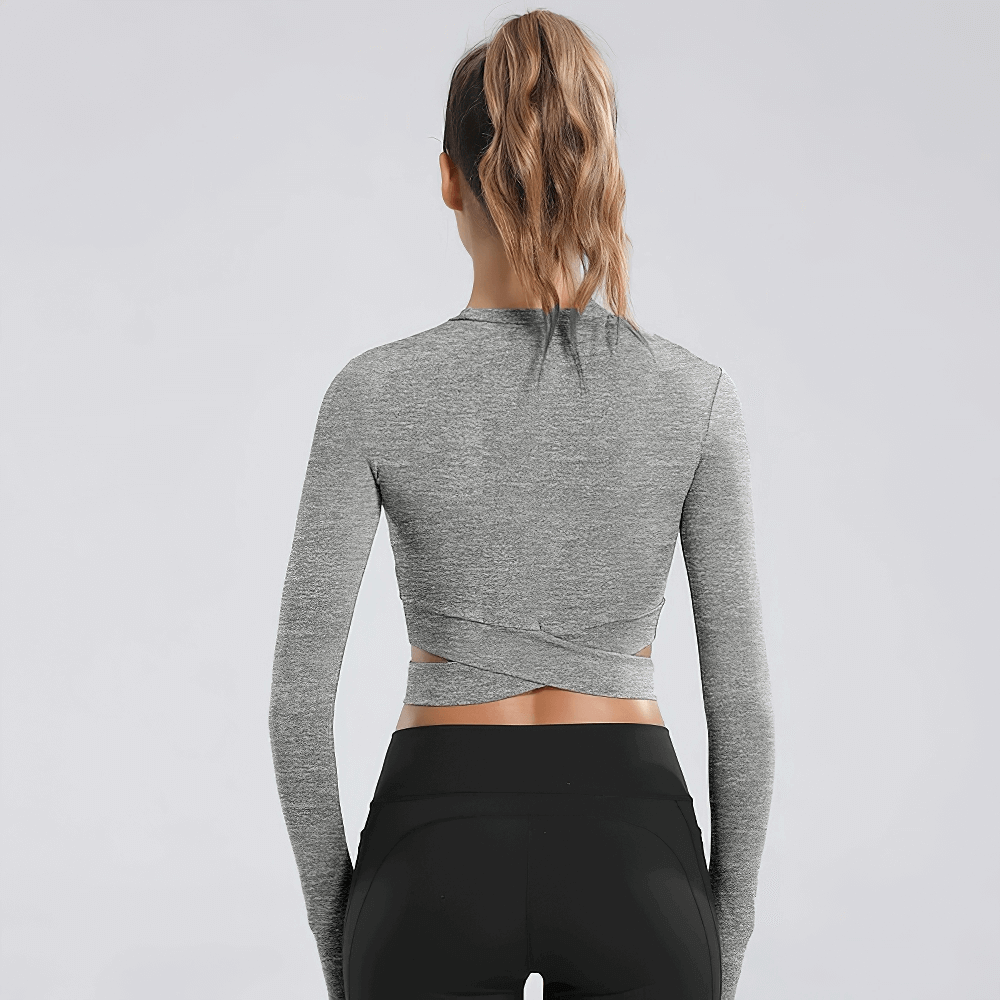 Back view of a gray long sleeves fitness top for women with a cross waist design, perfect for yoga. Slim-fit crop top with breathable fabric.